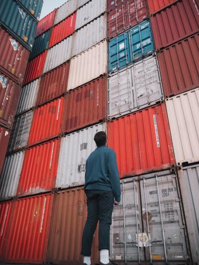 person looking up at stack of shipping containers
