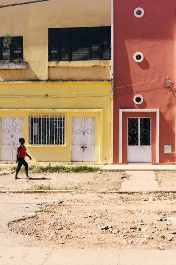 A person walks past yellow and red buildings.