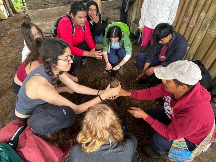 Laidlaw scholar hands a clump of a soil to an Ecuadorian man.