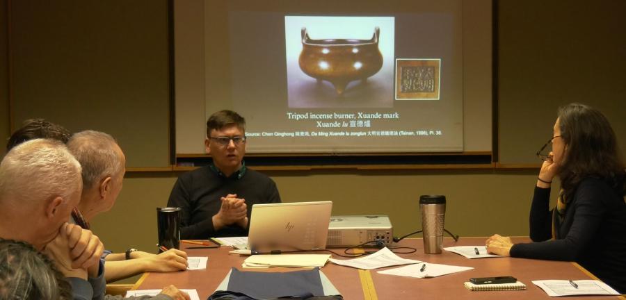 photo of colloquium session people with slide of incense burner in the background