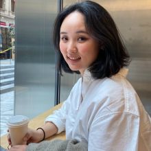 Chloe has shoulder length bob white blouse and sits next to a stainless steel wall and window