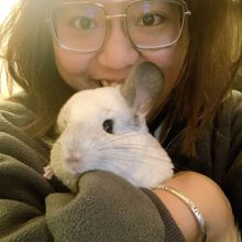 Yu Liang wears glasses as she holds a bunny in her arms and smiles