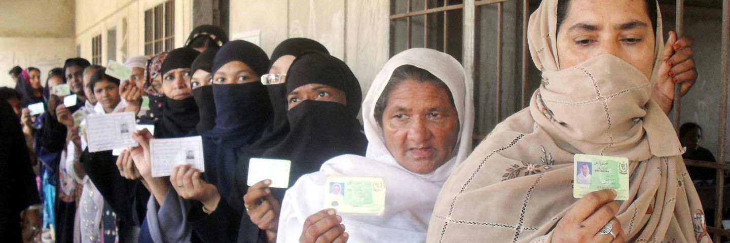 Women holding up ID cards to vote in Karachi, Pakistan