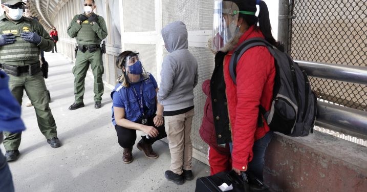 Asylum seekers stand in line with border control agents