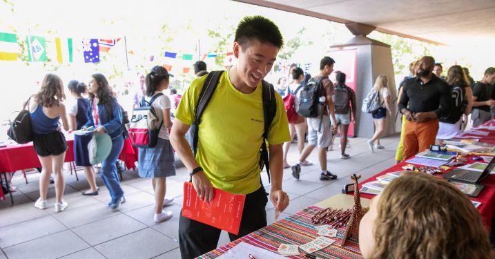 Student at international fair talking with person at table