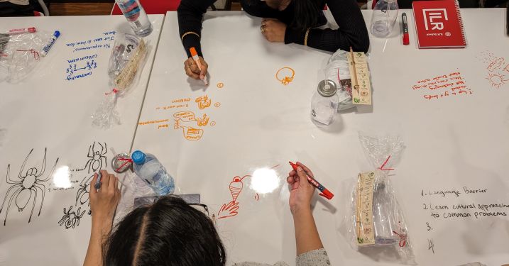 Students brainstorm ideas on a whiteboard table.