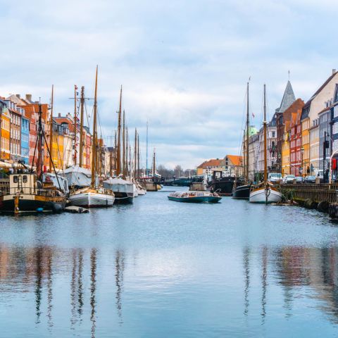 Canal in Copenhagen with boats and colorful buildings lining each side of the waterway.