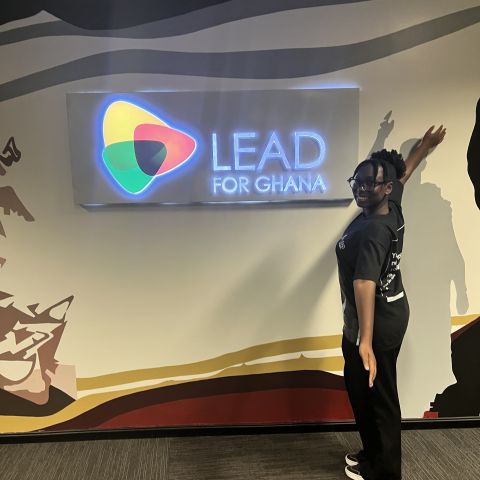 Eliana Amoh holds her arms open to wide to display a "Lead for Ghana" sign.