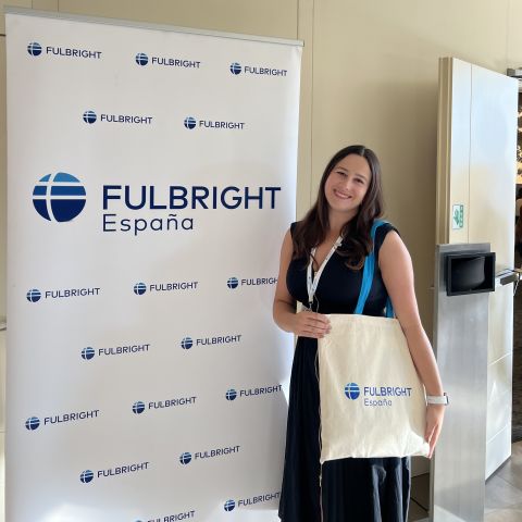 Alexis Fintland smiles for a photo next to a "Fulbright España" sign.