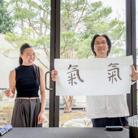 Calligrapher Wang Tiande holds up the work of an undergraduate student who drew Chinese characters.