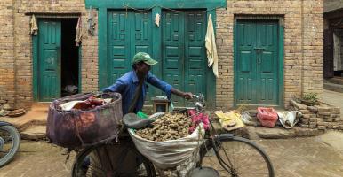 Man pushing bike with produce baskets in Nepal