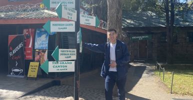 Intern stands next to a sign with many arrows pointing in all directions.